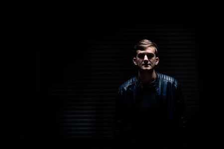 portrait of young man with leather jacket in dark garageの写真素材