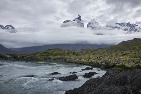 Cerro Paine Grande and the waters of the Paine River in Chilean Patagonia. Clouds cover the jagged mountains. Wide shot. Panorama.の写真素材