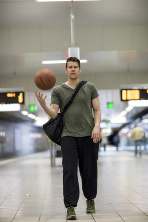 A man with a basketball and dressed in activewear standing at a subway station platform in Frankfurt, Germany. Long shot.のeditorial素材