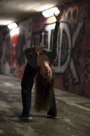 Female dancer in motion performing in an urban underpass. Full length. Selective focus.の写真素材