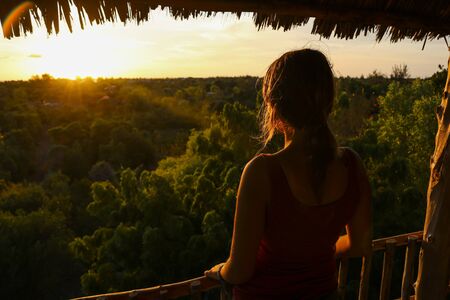 close-up of a woman looking at sunset from tree houseの写真素材