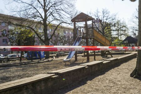 Children's playground with barricade tape preventing access during covid-19 quarantine. Focus on foreground.の写真素材
