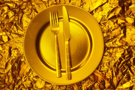 Stll life with plate, fork and knife on gold backgroundの写真素材