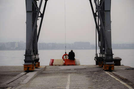 A man looking at the sea at Thessaloniki's portの写真素材