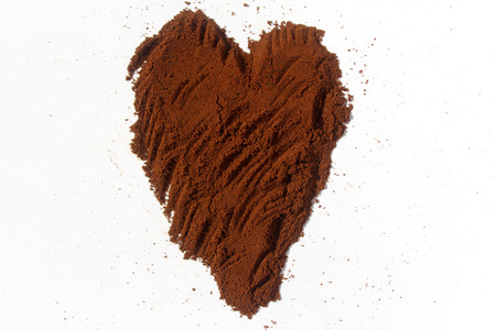 Ground coffee in shape of heart isolated on whiteの写真素材
