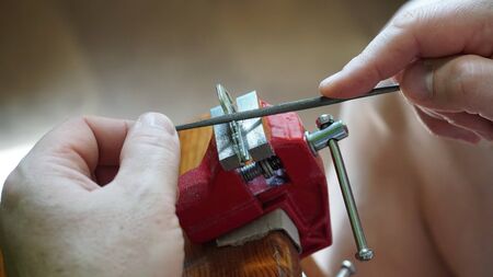 A person making a wrench and a nut with a rasp. Adjust the balance of the nut in the workshop. Repair worker. Close-up.の写真素材