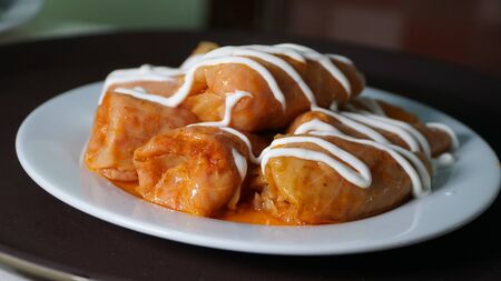 Stuffed cabbage under sour cream. A dish of Ukrainian cuisine cabbage rolls with sour cream on a white plate. nの写真素材