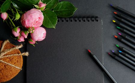 Notebook with pencils and flowers on a black background. Postcard, congratulation, business card. nの写真素材