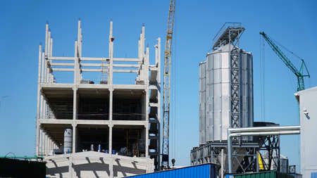 bearing pillars of the building. Structure building of steel structure roof truss frame installation by mobile crane under the construction building in the factory with blue skyの写真素材