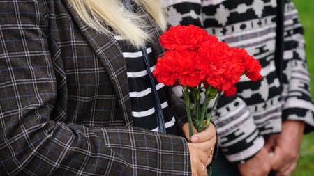 Woman with candle near black granite tombstone outdoors, focus on red rose. Funeral ceremony. nの写真素材
