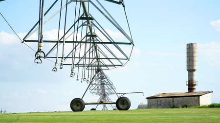 Garden field and irrigation equipment. Wheel line sprinkler irrigates field in fertile farm fields. Irrigation plant for watering green crops. Concept: agriculture or water supply. nの写真素材