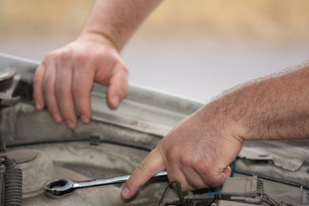 car repair, hands hold a metal key near the open hoodの写真素材