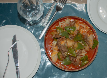 Lagman food from noodles and gravy from meat with vegetables in a ceramic plateの写真素材