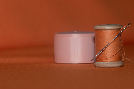 orange threads and needle on fabric and silk tape. sewing tools and accessories for creativity and sewing.の写真素材