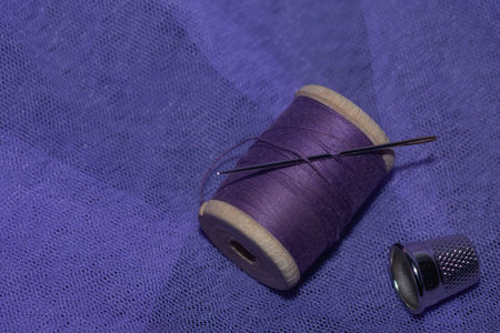 violet threads and sewing needle on lilac fabric. sewing accessoriesの写真素材
