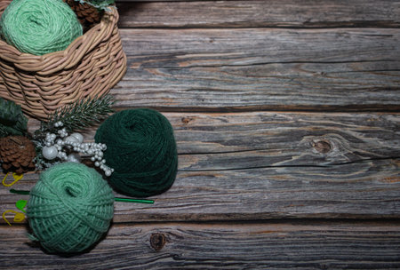 knitting, close up green yarn in backet on wooden background and Christmas decorative branch with...