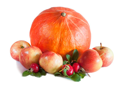 Orange pumpkin, five apples and rosehips with leaves isolated on whiteの写真素材