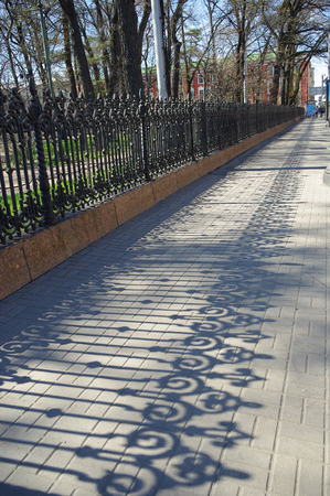 Wrought iron grille and its shadow on the sidewalk. Clear May day in the center of St. Petersburgの写真素材
