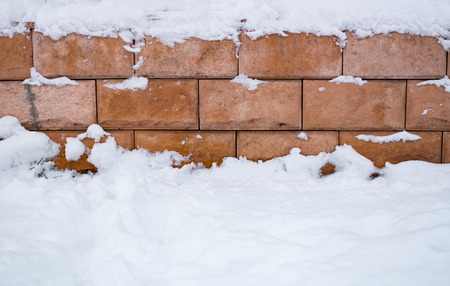 Red brick wall under snow in winter. Background in the daytimeの写真素材