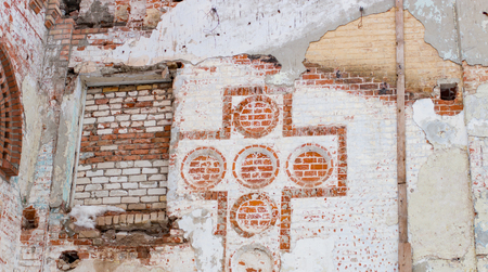 Old image of a christian cross in a brick wall in the daytimeの写真素材