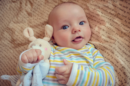 Beautiful baby hags a toy mouse and shows tongueの写真素材