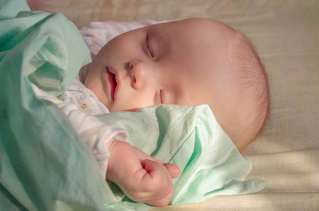 Cute sleeping baby with a hand on foreground in pastel tones