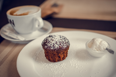 Muffin with ice cream and cup of cappuccinoの写真素材