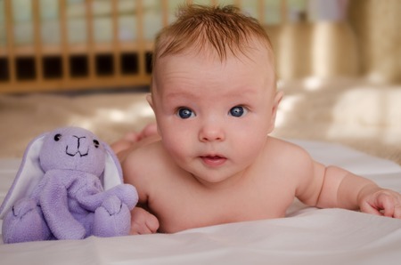 Close-up portrait of naked baby with a toy rabbitの写真素材