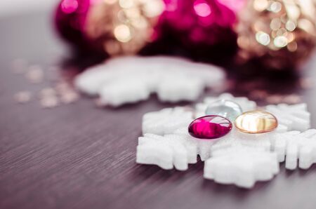 White snowflakes on background of magenta and gold xmas baubles with space for text. Merry christmas. Winter holidays. Xmas theme. Happy New Year. Blurred background.の写真素材