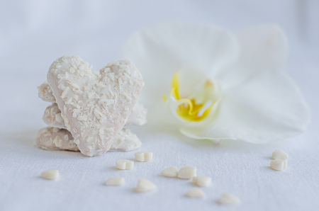 Cookie in shape of heart with small hearts and white orchid on light background.の写真素材