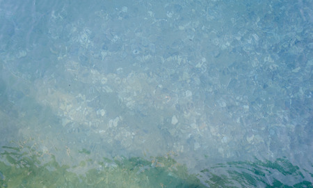 Transparent water of sea ocean and pebbles on the bottom. Sea water background. Sea bottom with...