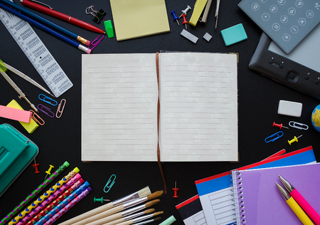 Back to school concept. School supplies with calculator and ebook on blackboard background with...