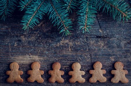 Christmas fir tree with gingerbread men cookies on old wooden background with space for text. Merry...