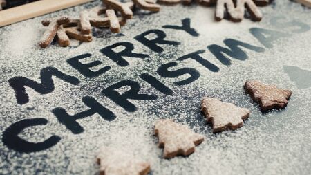 Wording Merry Christmas from homemade gingerbread cookies on dark chalkboard background. Christmas concept. Christmas moody style greetings card. Happy New Year. Selective focus.の写真素材
