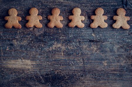 Christmas gingerbread men cookies on old wooden background with space for text. Merry Christmas and Happy New Year. Xmas baking concept. Top view. Copy space.の写真素材