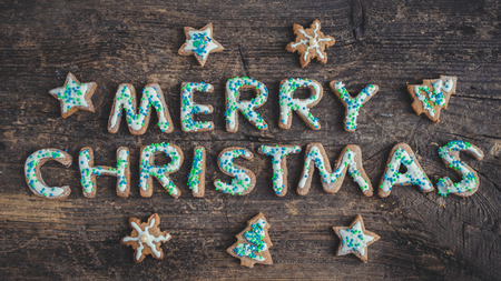 Wording Merry Christmas from homemade gingerbread cookies with icing on old wooden background. Christmas moody style greetings card. Happy New Year. Christmas concept. Top view.の写真素材