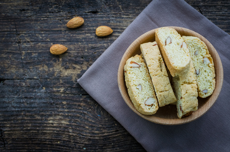 Italian cantuccini cookies in a bowl with almonds. Traditional italian almond cookies biscotti on wooden background. Homemade Almond cookies with space for text on wooden table. Top view. Copy space.の写真素材
