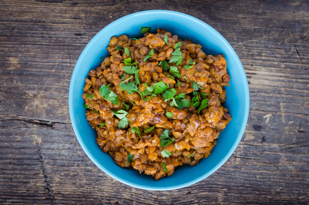 Frash lentil stew with bolognese sauce in a bowl with parsley on rustic wooden table. Italian food concept. Heathy vegetarian food. Top view.の写真素材