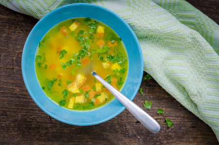 Zuppa Imperiale - Italian soup with eggs and Parmesan cheese, dish of Emilia Romagna. Imperial soup on wooden table. Omelet in chicken broth with parsley in a bowl. Italian cuisine concept. Top view.の写真素材