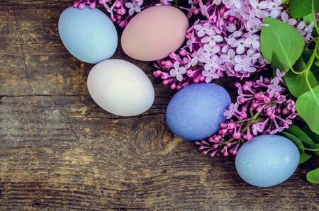 Easter background with handmade painted purple eggs and lilac on a wooden vintage board with place for text. Top view. Copy space.の写真素材