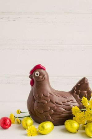 Easter composition with chocolate chicken and eggs with yellow flowers on white shabby chic wooden background with place for text. Copy space.の写真素材