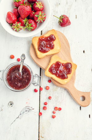 Toasts with strawberry jam for breakfast on white rusric wooden background. Top view.の写真素材