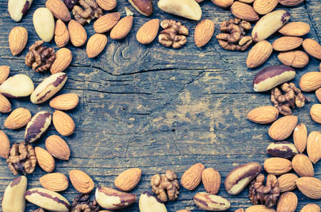 Concept - Nuts mix on old rustic wooden table. Almonds, Brazil nuts and walnuts background. Healthy edible seeds food ingredient on the table. Top view. Directly above.の写真素材