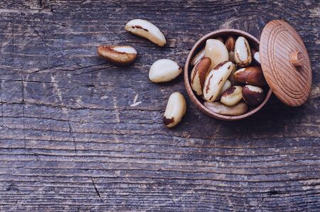 Tasty Brazil nuts from Bertholletia excelsa tree in wooden bowl on the old background with place for...