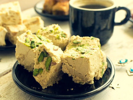 Traditional eastern dessert - halva pistachio and cup of coffee. Arabian sweets on wooden table....