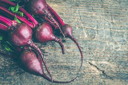 Pile of homegrown organic young beets with green leaves on the table. Fresh harvested beetroots on...