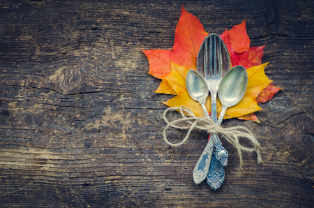 Thanksgiving autumn place setting with cutlery and arrangement of fall leaves and rope on wooden background with place for text. Thanksgiving holidays background concept. Copy space. Top view.の写真素材