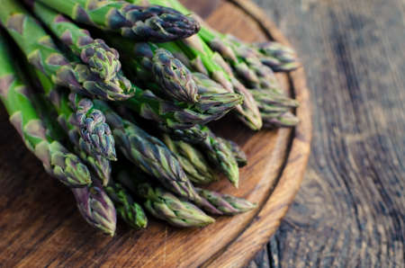 Bunch of fresh green asparagus on wooden board on an old table. Healthy food concept.の写真素材