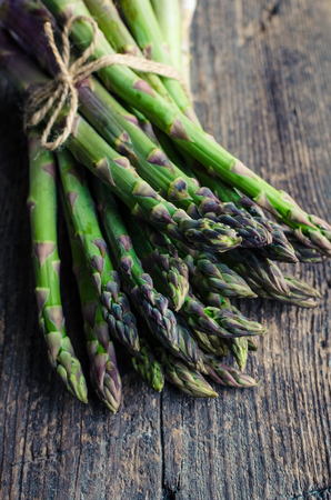 Bunch of fresh green asparagus tied with twine on an old wooden background. Healthy food concept. Top view. Copy space.の写真素材