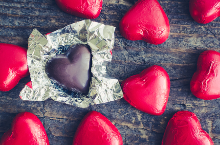 Valentines Day background with red chocolate heart shaped candies on a rustic wooden table. Romantic love concept. Valentine's greetings card. Top view.の写真素材